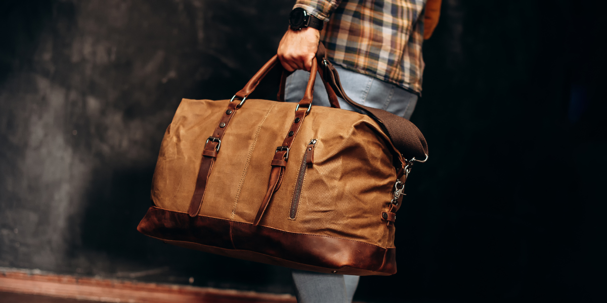 Homme portant un sac de voyage en cuir