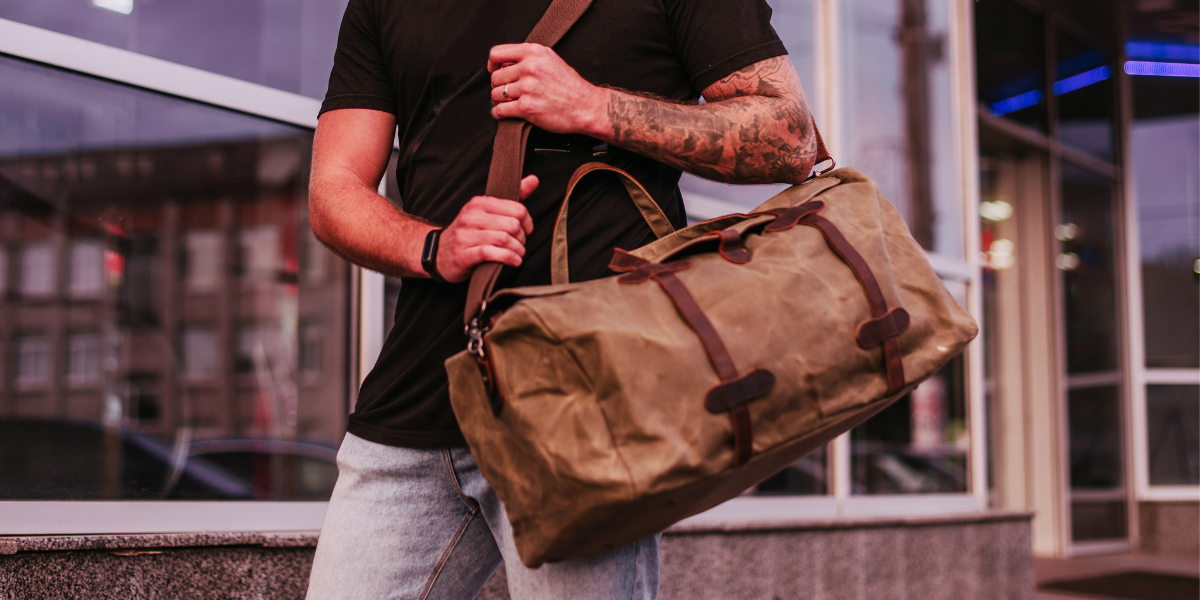 Homme portant un grand sac de voyage en cuir