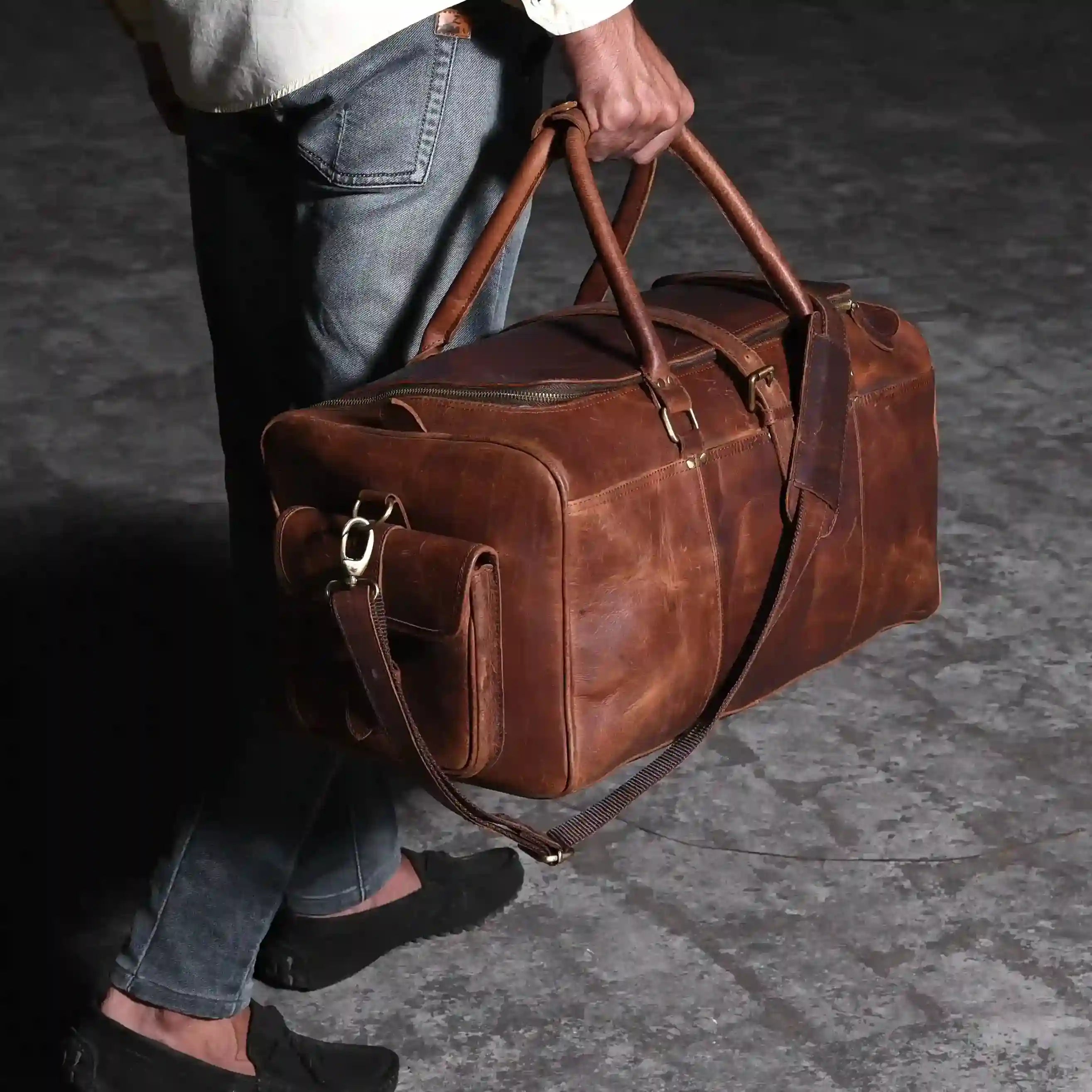 Homme portant une grande sacoche de voyage en cuir